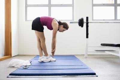 Young woman doing stretches on a mat at the gym.