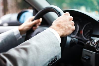 Close up of hands on a steering wheel.