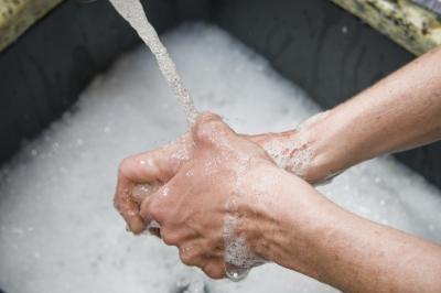 A woman washes her hands wtih soap and water.
