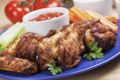 Chicken wings with a side of sauce and cut vegetables