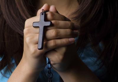 woman praying and holding cross