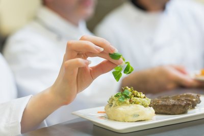 A chef putting a garnish on mashed potatoes.