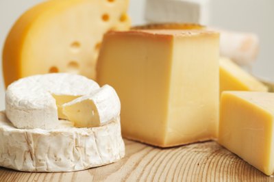 A variety of cheese on a cutting board.