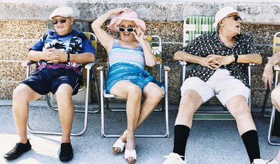 Senior men and women sunbathing on patio chairs.