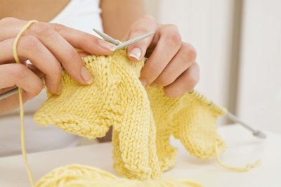 hands knitting with yellow yarn
