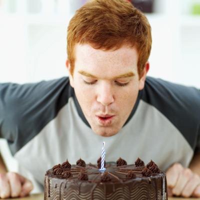 Man blows out candle on birthday cake