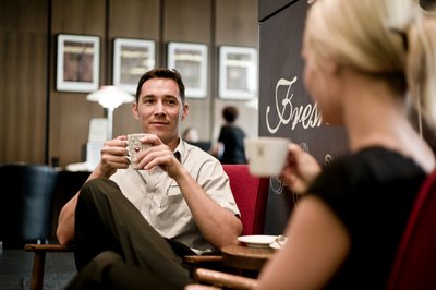 Two people chat inside of a coffeehouse.