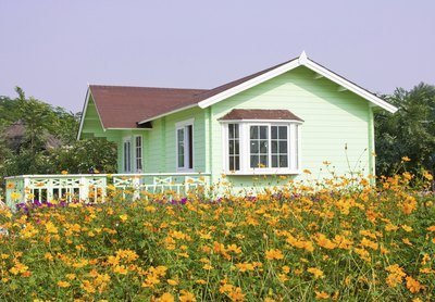 A spring green cottage with white trim and brown accents in a country meadow.