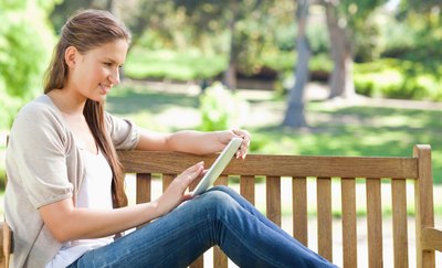 Woman reading an e-book on park bench