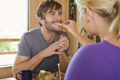 A woman gives a man a bite of food.