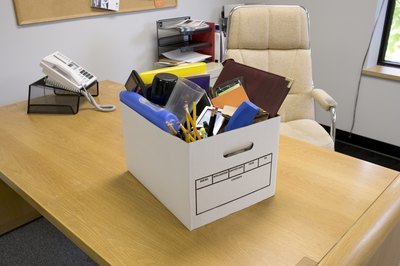 Box with office belongings on desk, symbol of unemployment.