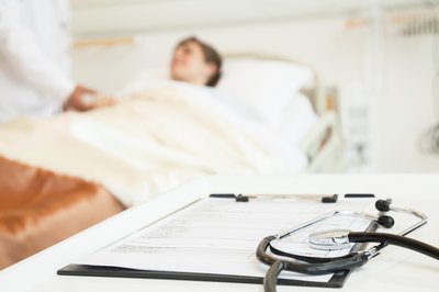 Stethoscope and medical chart with hospital patient in background