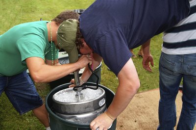 Man drinking keg beer while doing a hand stand