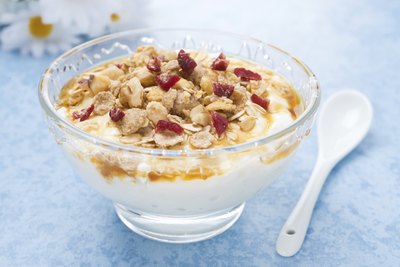 Glass bowl of yogurt topped with granola.