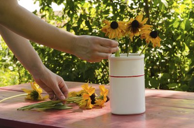 A woman filling a vase with freshly picked black-eyed susans.