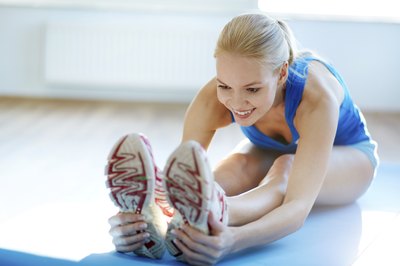 A woman stretches at a gym.