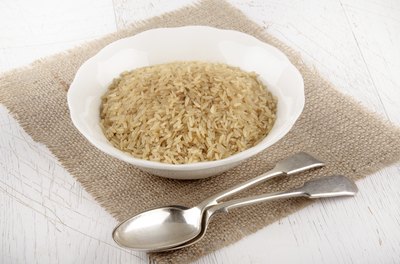 A bowl of uncooked brown rice on a jute placemat.