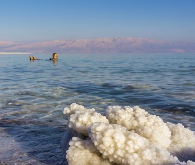 Woman floating in the Dead Sea, Mountains in background are in Jordan