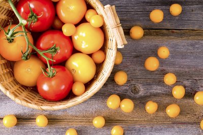 An overhead view of a basket of red and yellow tomatoes.