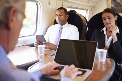 People using portable devices during a morning train commute.