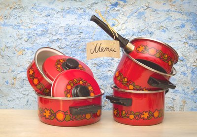 Cooking pots from the 1970s with a handwritten sign that reads, "Menu", attached to one.