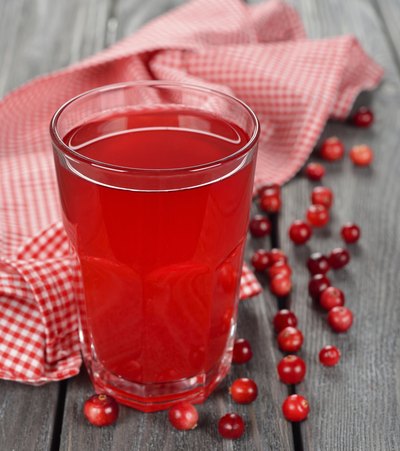 A glass of cranberry juice on a table with cranberries