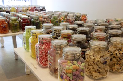 Jars of assorted bulk candies on tables in a candy store.