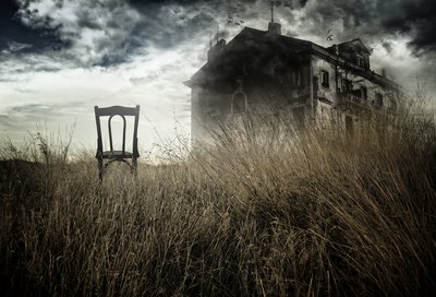 Chair in field next to old house