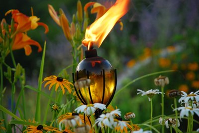 A tiki torch sits amongst tropical flowers.