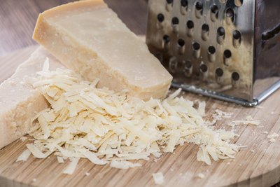 Grated Parmigiano-Reggiano cheese on cutting board.