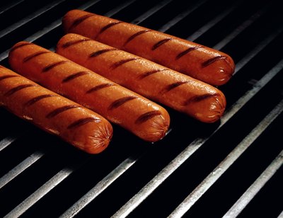 Ht dogs cooking on a grill.