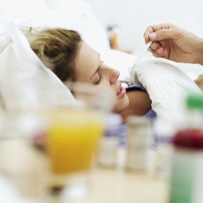 Woman in bed having thermometer placed in mouth
