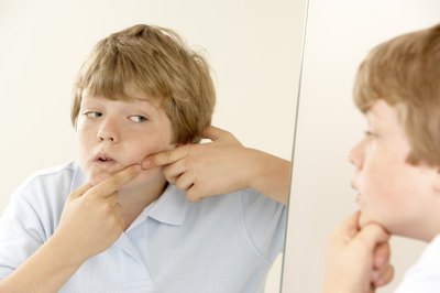 Tween boy touching pimple on face
