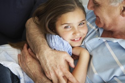 A grandfather hugs his granddaughter.