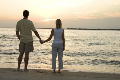 A couple holds hands and watches the sunset.