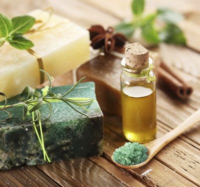 Natural soaps next to a bottle of essential oil and herbs