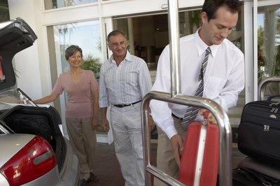 A hotel employee assists guests with their luggage.