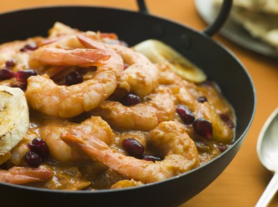 A bowl of prawns, black bean, and plantains slices on a kitchen table.