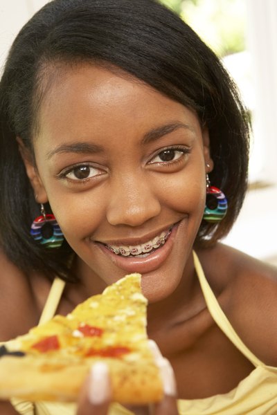 Girl with braces eating a slice of pizza