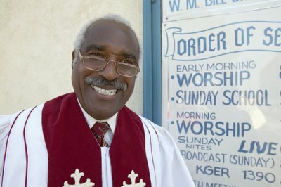 A clergyman wears a red sash over his robe.