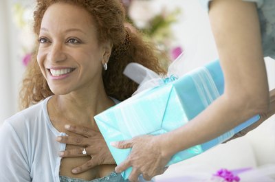 A woman happily recieves a present.