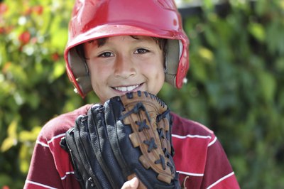Child in baseball helmet holding up glove