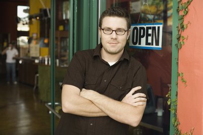 A cafe owner stands in front of his place of business.