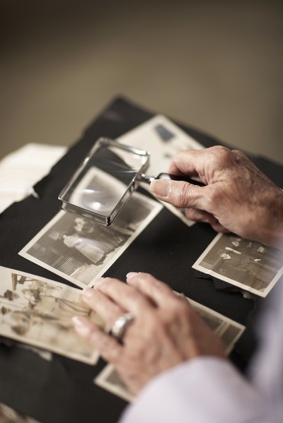 A woman looks through a photo album with a magnifying glass.