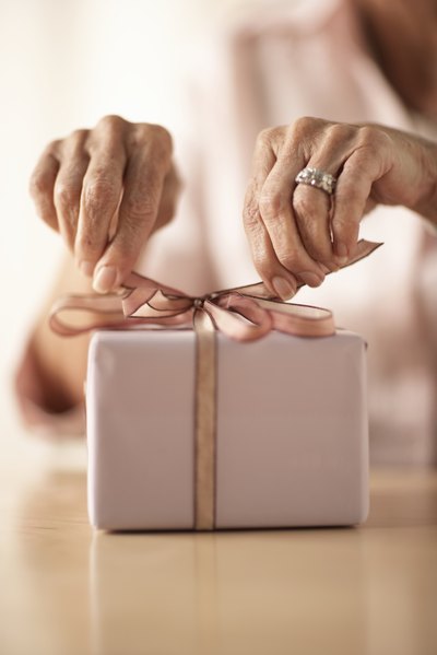 Close-up of woman tying a bow on top of gift.