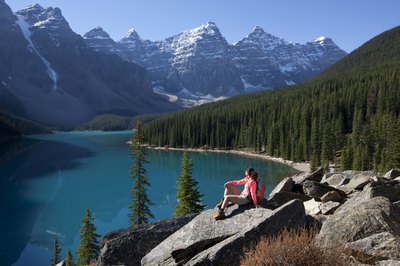 A woman hikes near a mountain lake in the Rockies.