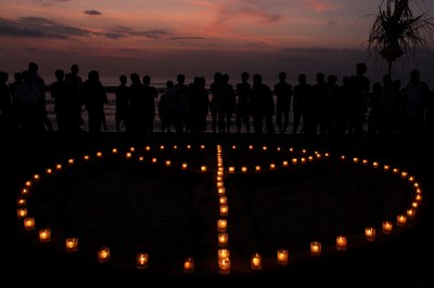 People surround symbol made with candles