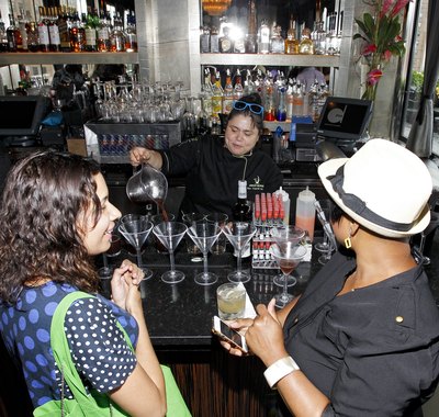 Female bartender pours drinks and talks with guests