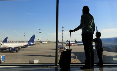 Mother and son with luggage looking at airplane.