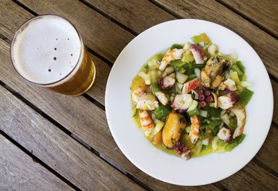 An overhead view of a seafood dish and a pint of beer.
